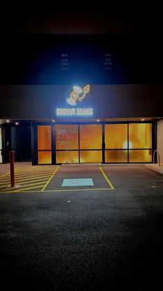 The glowing Groove Beans record sign above the shopfront at night